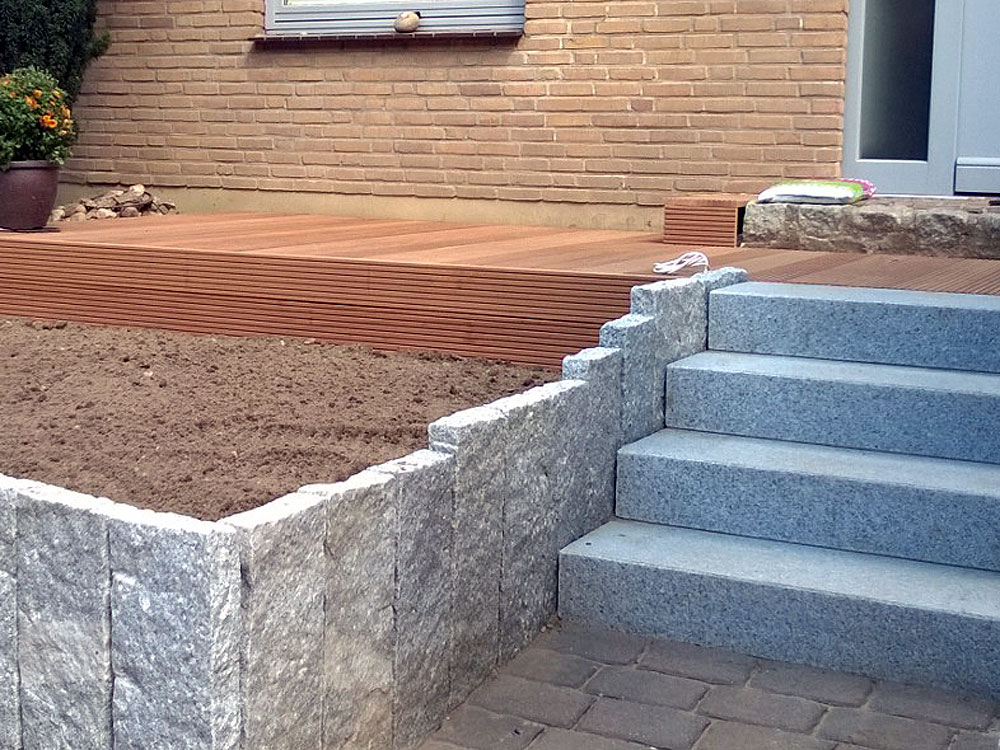 Neu gesetzte Granitsteelen und Treppe aus Granit, Terrasse aus Bangkirai-Holz mit Dekotisch neben Haustür